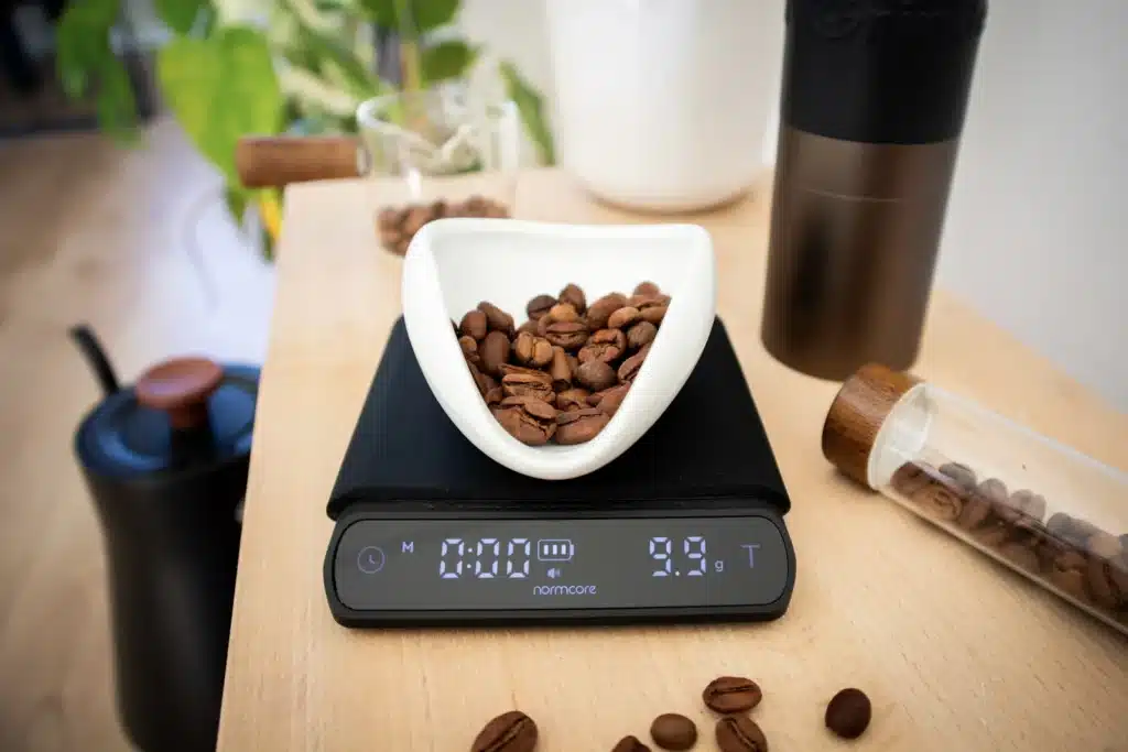 Granos de café pesados en una balanza digital para calcular cuántos gramos usar por taza